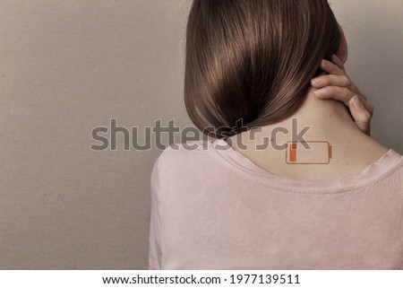 A tired woman and a picture of a dead battery on her. A symbol of lack of energy and fatigue in a person Royalty-Free Stock Photo #1977139511