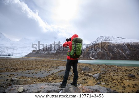 Woman photographer taking pictures in winter high altitude mountains