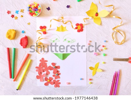 A child is making a card of a summer princess girl with flowers, paper craft, plasticine, beads, coloful clay and applique,  Craft for children.