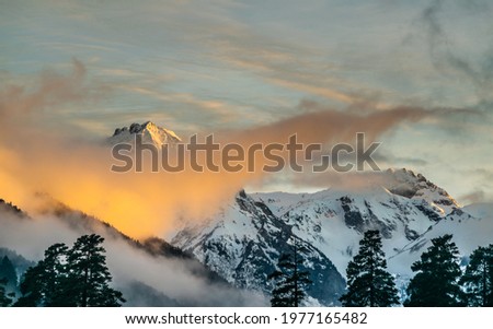 Snow covered mountain peaks and colorful clouds over mountain range during sunset, Arkhyz villadge, Caucasus mountains, Russia Royalty-Free Stock Photo #1977165482