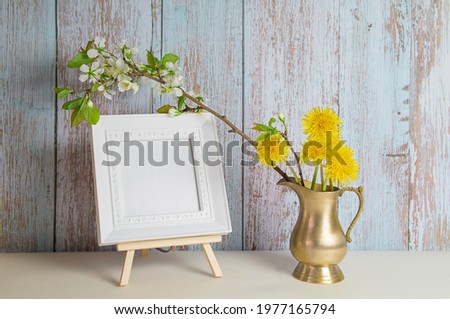 Dandelion bouquet and cherry blossoms in a vase and picture frame with copy space for mockup. High quality photo