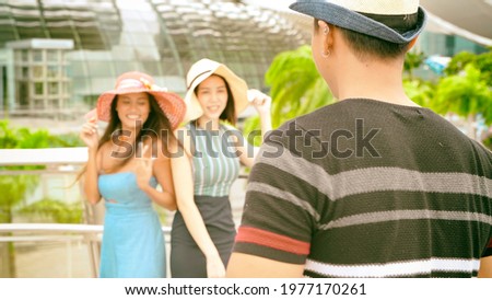 Three asian young friends enjoy outdoor time taking pictures along the city streets.