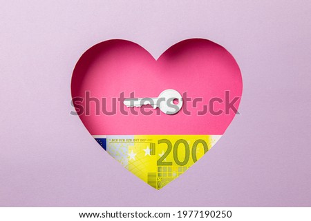 The key to the door and the two hundred euro banknote are in a pink heart on a purple background. Minimal concept of money, love and real estate.