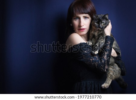 Studio shot of dark woman with european common cat isolated on blue background