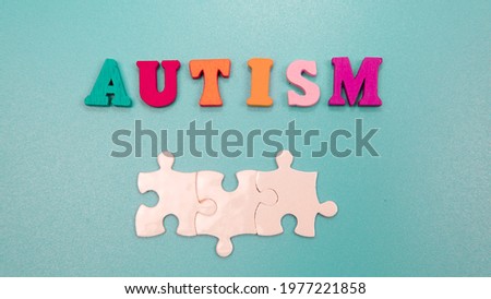 Selective focus of wording Autism and three piece of puzzle with isolated blue background