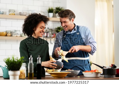 Happy smiling couple cooking together. Husband and wife preparing delicious food.	