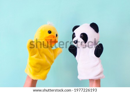 Puppet theater toys on a hand on a turquoise background. Childrens entertainment concept. Duck and panda