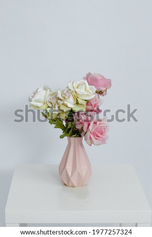 Pink vase with flowers on the table on a white background. Space for text. Close-up.
