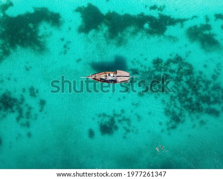 Aerial drone view on a boat in the blue water of a coral reef with floating people