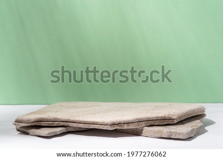 Background for cosmetic products of natural green color. Stone podium on a green background. Front view. Royalty-Free Stock Photo #1977276062
