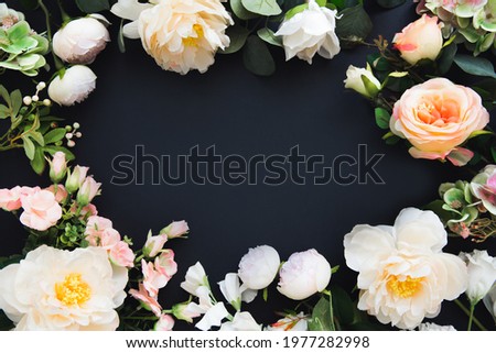 Frame of flowers. Summer blooming delicate peonies and roses on black background, festive background, greeting card layout. Copy space.