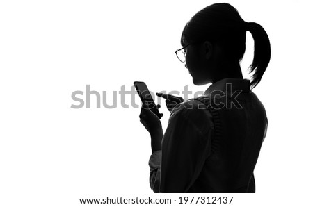 Silhouette of asian school girl using a smart phone.