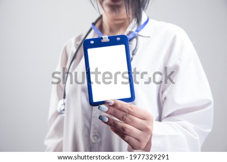 female doctor holding ID tag on gray background