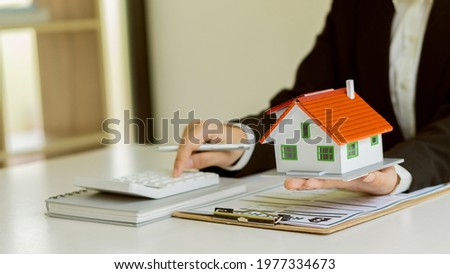 Real estate agent advising clients with contract documents and computers with front view house designs