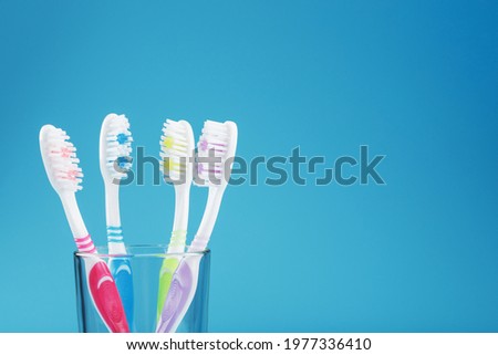 Colorful toothbrushes in a glass on a blue background. The concept of oral health care for the whole family. Free space
