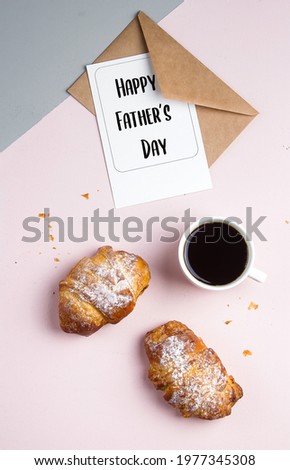 Flat lay with cup of coffee, croissants, postcard with text Happy Father's Day on pink grey background. Breakfast Holiday Morning concept.