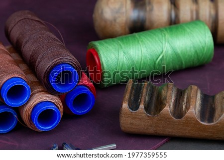 Colored thread spools for sewing leather are placed on a table in the workshop