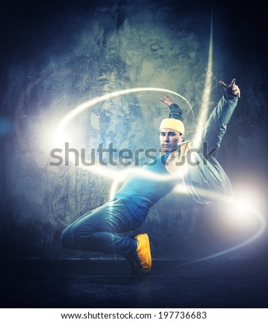 Stylish man dancer showing break-dancing moves with magic beams around him 