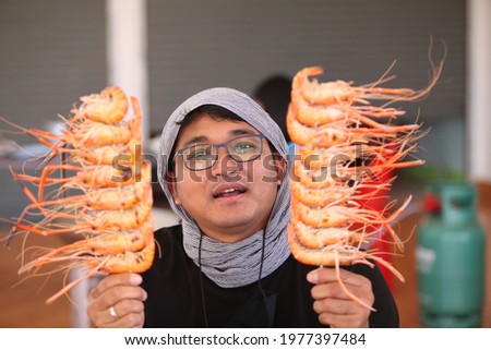 A man with grilled shrimp on a skewer