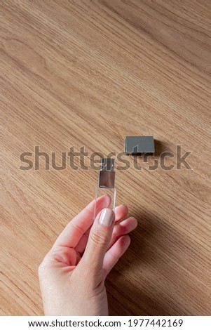woman's hand holding a pen drive with a wooden table background