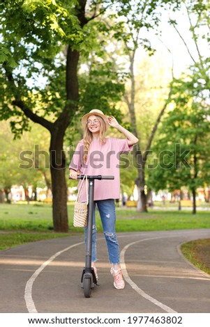 girl on a scooter in the park in the summer on a walk