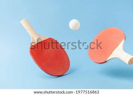 Red  ping pong table tennis paddle rackets with ball on blue background. Summer sport activity concept. Flying Royalty-Free Stock Photo #1977516863