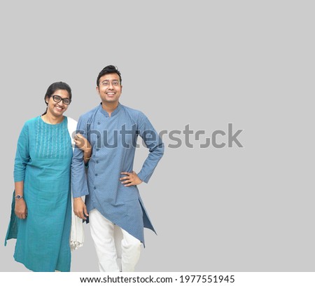 A closeup shot of a smiling Bengali couple in traditional ethnic clothes on a gray background Royalty-Free Stock Photo #1977551945