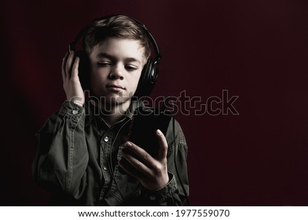 Tinted image of a little boy listening to music with headphones on his phone