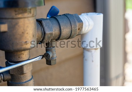 Using a flathead screwdriver to close the test cock next to the vacuum breaker to startup a sprinkler irrigation system in the spring Royalty-Free Stock Photo #1977563465