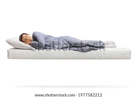 Full length shot of a man in pajamas sleeping peacefully on a floating mattress isolated on white background Royalty-Free Stock Photo #1977582212