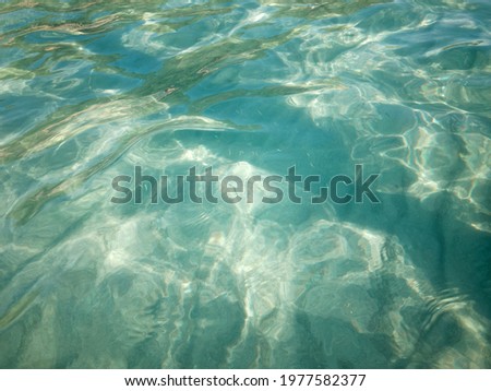 Shining blue sea water ripple background view through to sand floor