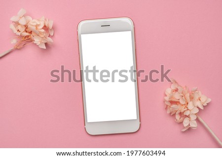 Mobile phone mock up and white flowers on pink background.Spring pastel colour top view