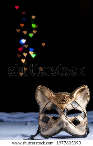 A vertical shot of carnival mask with cat form on a dark with bokeh heart background