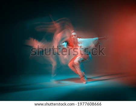 Mixed race young girl dancing in colorful neon studio light. Long exposure. Contemporary hip hop dance