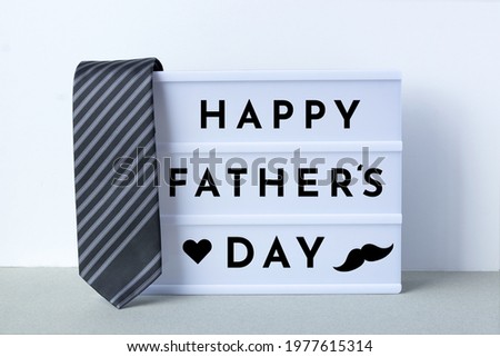 Happy Father’s Day Concept. Happy Father’s Day wishes on light box with tie and mustache
