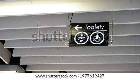A sign showing the way to the toilets hanging from the roof