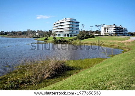 Photography of a beautiful lagoon, its coast and a building and palm trees at the horizon