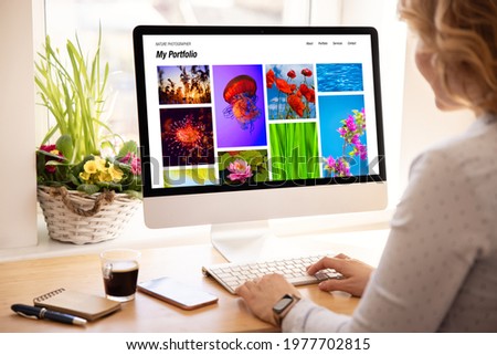 Woman viewing photography portfolio website on computer screen Royalty-Free Stock Photo #1977702815
