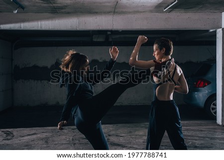 Silhouette picture of two young women practicing fighting inside the garage.