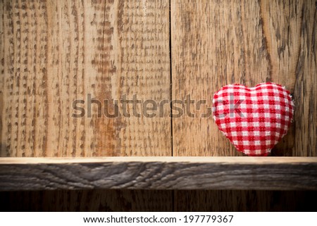 Heart on a wooden shelf. Wooden wall, studio photography.