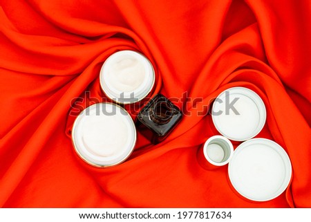 face care creams in gold color on bright red satin fabric