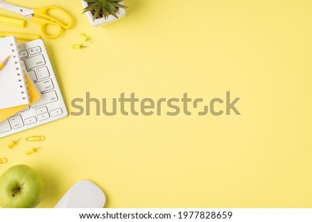 Overhead photo of notepad plant pencil pen keyboard felt-tip paperclips computer mouse and apple isolated on the yellow background with empty space