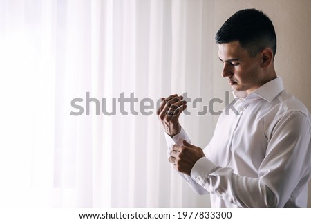 Morning preparation of grooms, handsome man gets dressed and prepares for the wedding. Royalty-Free Stock Photo #1977833300