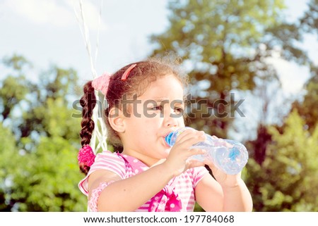 Little child holding the bottle and drink water