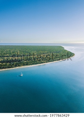 Aerial view of a sailboat anchored offshore from a beautiful beach