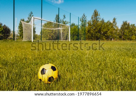 Ball on soccer field with football goals on background