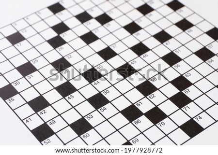 Black and white crossword puzzle in a newspaper. No words have been entered yet. Narrow depth of field