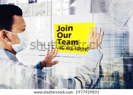 Double exposure of businessman wearing face mask while attaching a paper with join our team text on the office door with cityscape background