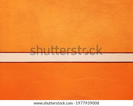 Orange wall of a renovated italian house,  textured background with decorative white band.