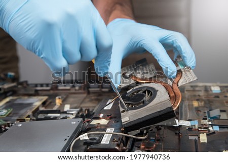 a man disassembles a laptop on a gray background